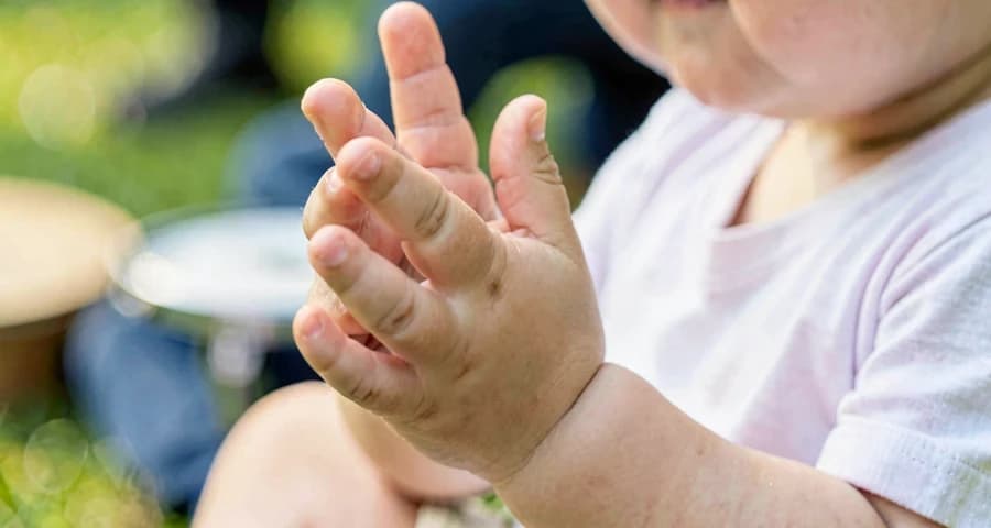 mãos de bebê batendo palmas durante atividade musical na creche