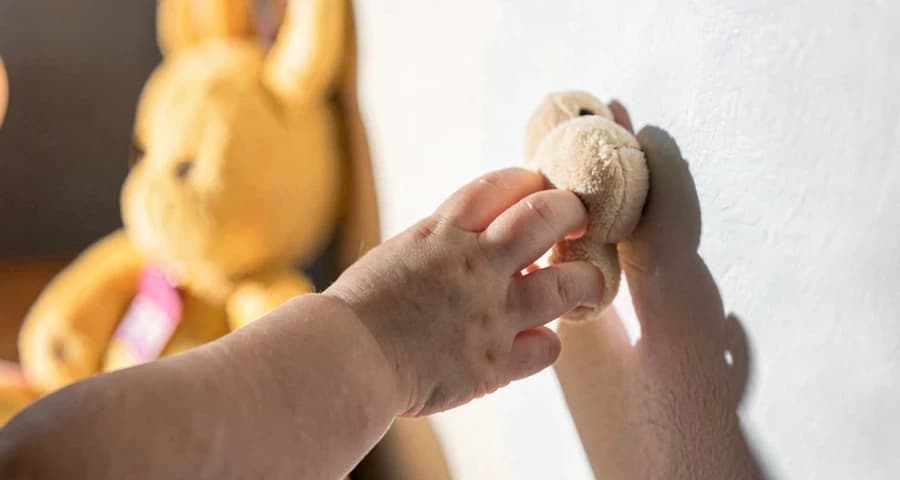 Exploração de sombras com bebê: mão infantil tocando brinquedo com sua sombra projetada na parede