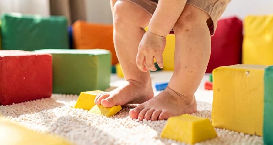 desvio de obstáculos creche: detalhe dos pés de criança pequena sobre almofada de espuma durante atividade motora