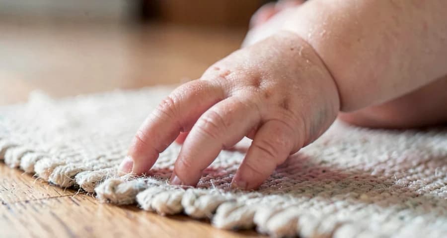 mão de bebê tocando tapete de textura durante percurso sensorial na creche