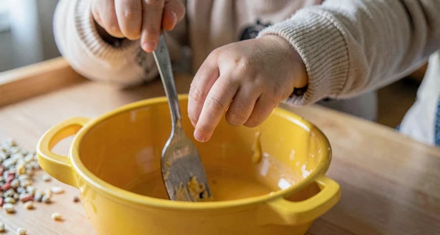 bebê mexendo panela de brinquedo durante atividade de faz de conta na creche