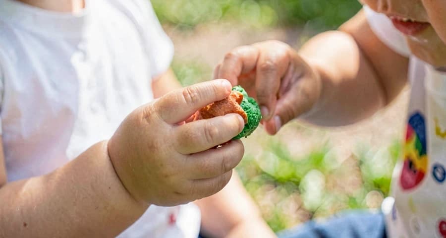 criança da creche servindo comida de brinquedo para colega em atividade de faz de conta