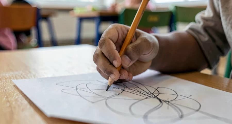 Motricidade fina na creche: criança segurando lápis de grafite e fazendo traços no papel