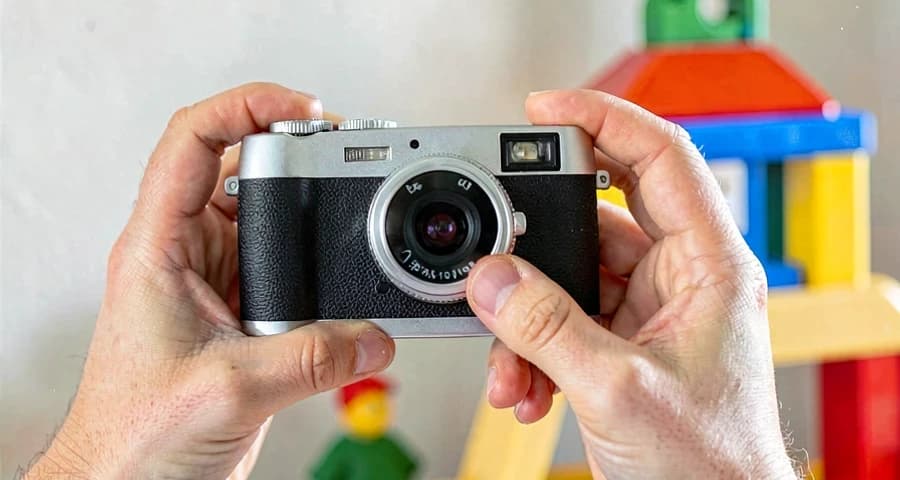 mãos de criança segurando câmera durante atividade de registro fotográfico na creche