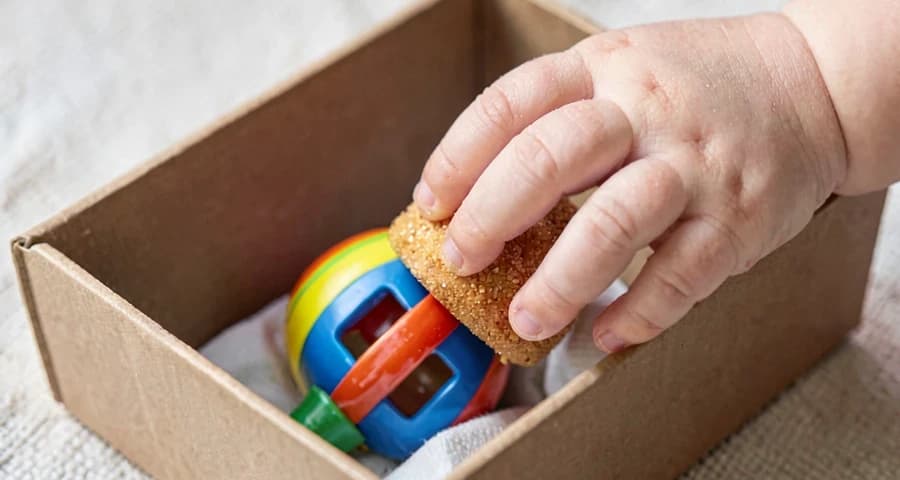 bebê segurando chocalho retirado de caixa sonora durante atividade na creche