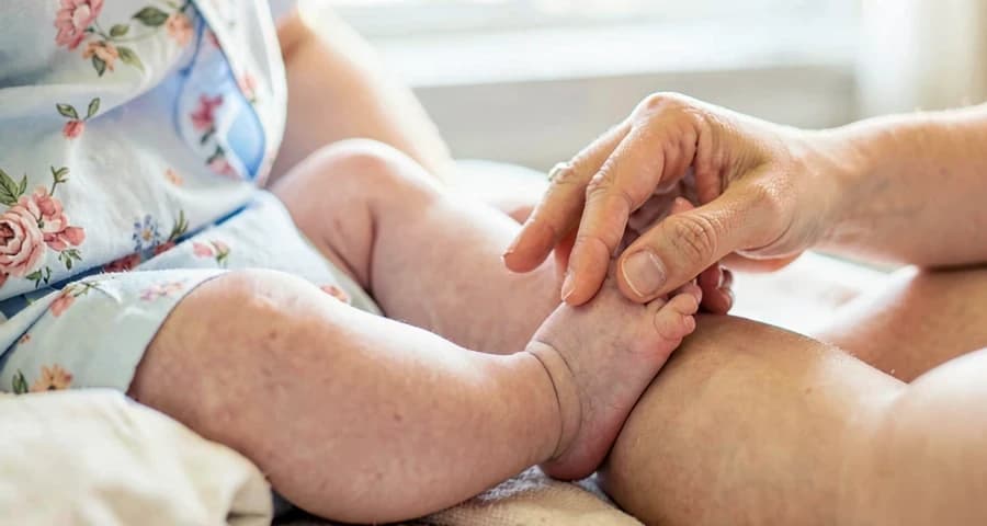 educadora massageando o pé de bebê durante atividade de relaxamento na creche